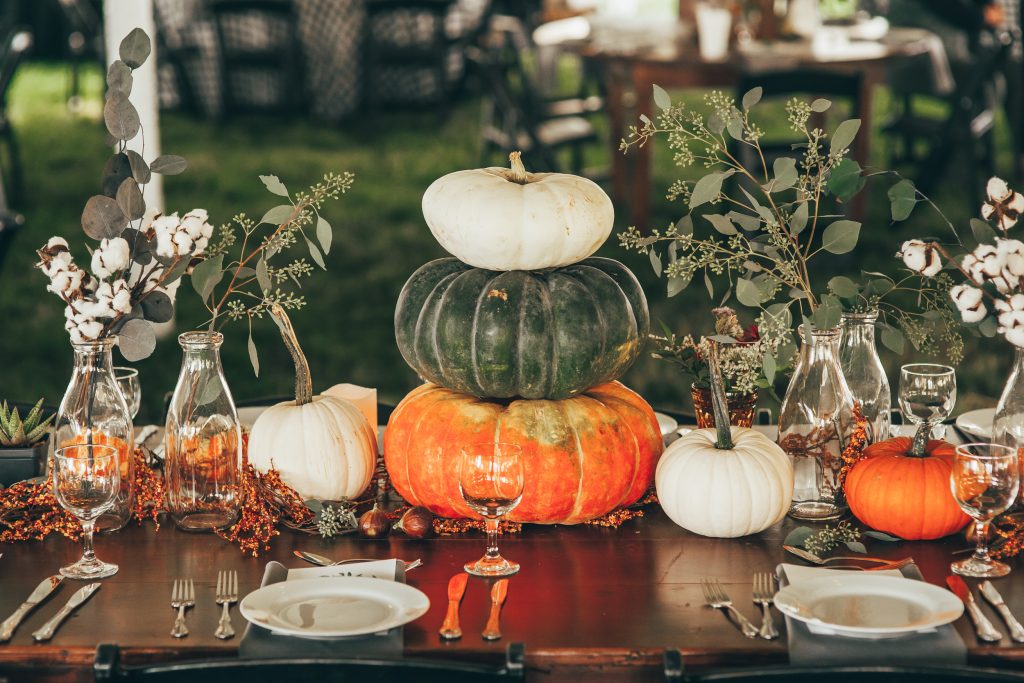 fall table vignette with lots of small pumpkins and greenery