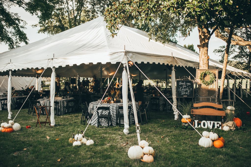 white tent over dinner tables decorated for fall