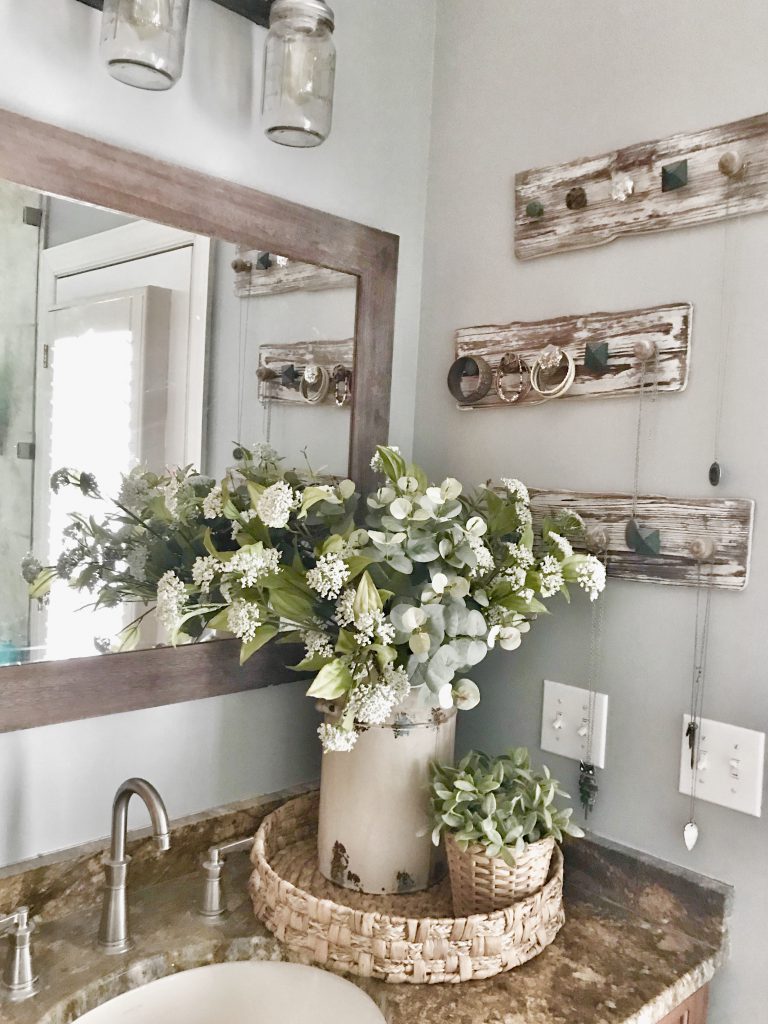 bathroom vanity with jewelry hanging on wooden pegs